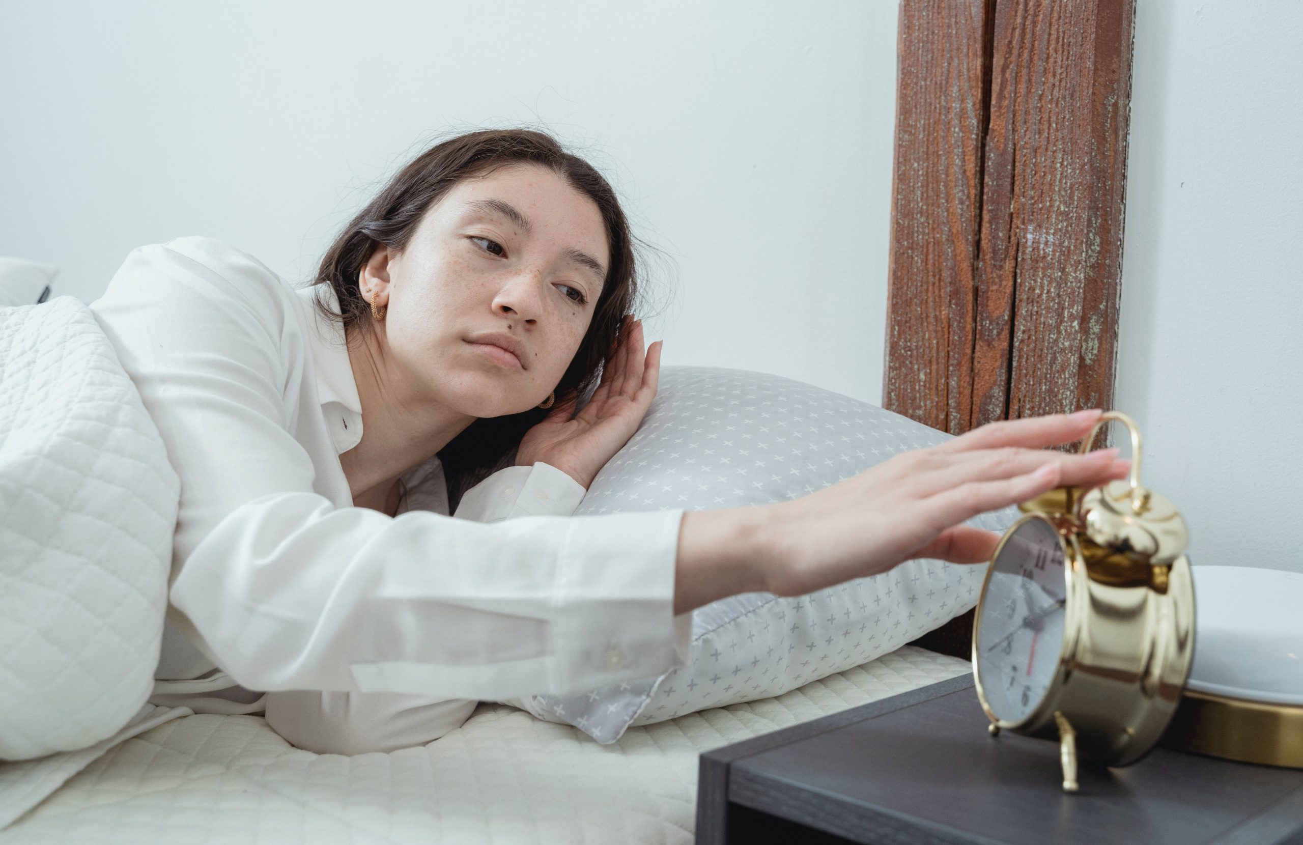 Young woman waking up with alarm clock.